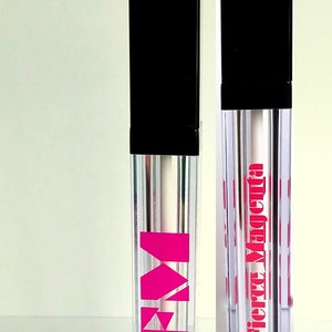 May include: Two clear lip gloss tubes with black caps. The tube on the left has a pink "M" logo. The tube on the right has the text "Fierce Magenta" in pink letters.