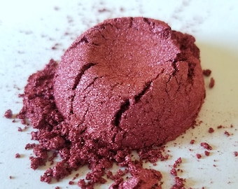 May include: A pile of loose, red mica powder with a shimmery finish. The powder is a deep red color with a slight pink hue.