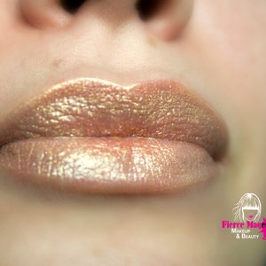 May include: Close-up of lips wearing a shimmery gold and brown lipstick. The lipstick has a fine glitter finish.