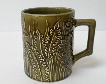 Vintage ceramic mug in olive green glaze and linear leaves/butterflies around it, decoration only (damaged)