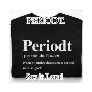 以下が含まれることがあります： 大きな白い文字で「Periodt」と書かれた黒いTシャツ。その下に定義があり、下部には「Say it Loud」というフレーズがあります。シャツはきちんと折りたたまれています。