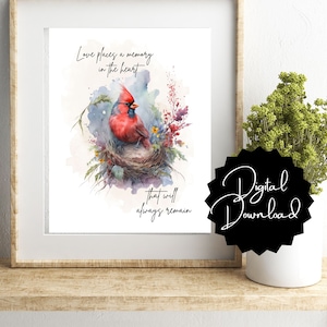 May include: A watercolour painting of a red cardinal sitting in a nest with flowers and greenery. The quote "Love places a memory in the heart that will always remain" is written below the bird.