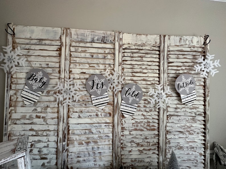 K&ouml;nnte beinhalten: Ein wei&szlig;-graues Babyparty-Banner mit Schneeflocken und dem Text "Baby, It's Cold Outside".