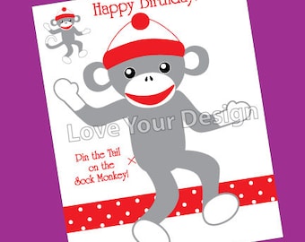 Puede incluir: Tarjeta blanca con una ilustración de un mono calcetín. El mono es gris con un gorro y boca rojos. El texto incluye "Happy Birthday!" y "Pin the Tail on the Sock Monkey!" en rojo. Una cinta roja con lunares está en la parte inferior.