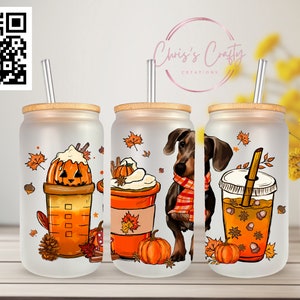 Puede incluir: Tres vasos de vidrio esmerilado con tapas y pajitas, con diseños de temática otoñal. Los diseños incluyen un latte de especias de calabaza, un dachshund con una bufanda y un café helado de especias de calabaza.