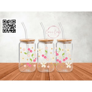 May include: Three clear glass tumblers with bamboo lids and straws. Each tumbler features a design of pink cherries, white flowers, and gold stars.