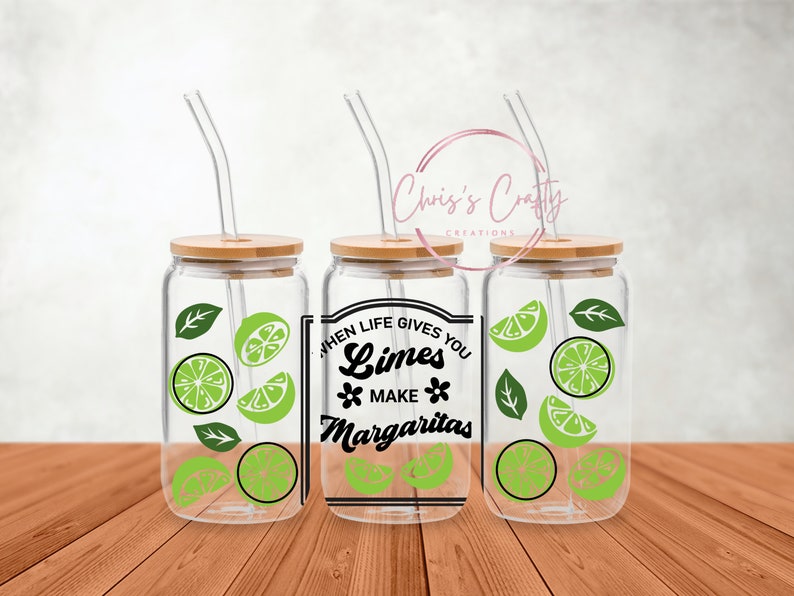 May include: Three clear glass mason jars with bamboo lids and reusable straws. Each jar has a lime and leaf design and the text "When life gives you limes make margaritas".