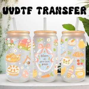 May include: Three frosted glass tumblers with bamboo lids and metal straws, featuring colorful illustrations of books, pastries, flowers, and a central frame with the text "Bloom at your own pace" surrounded by a pink bow and blue scalloped border.