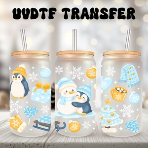 Könnte beinhalten: Drei Gläser mit Milchglas-Effekt mit Bambusdeckeln und Metallstrohhalmen. Jedes Glas zeigt winterliche Illustrationen, darunter Pinguine, Schneemänner, Schneeflocken und Ornamente. Der Text "UVDTF TRANSFER" befindet sich oben.