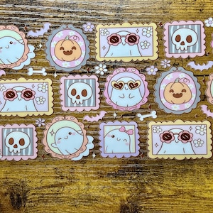 Könnte beinhalten: Eine Sammlung von Halloween-Stickern mit niedlichen Geistern, Kürbissen und Totenköpfen in dekorativen Rahmen. Die Sticker sind in Pastellfarben gehalten und haben florale und Fledermaus-Akzente, ideal zum Basteln oder Dekorieren.