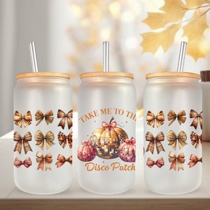 Puede incluir: Tres vasos de vidrio esmerilado con tapas de bambú y pajitas transparentes. Cada vaso presenta un diseño diferente. Un vaso tiene una calabaza con el texto "Take Me To The Disco Patch". Otro vaso tiene un patrón de lazos marrones. El tercer vaso tiene un patrón de lazos marrones.