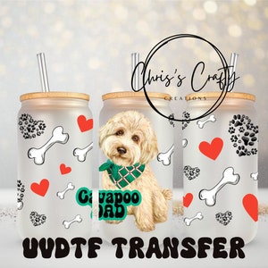 Puede incluir: Vaso de vidrio esmerilado en forma de lata con tapa y pajita de bambú. El diseño presenta una ilustración de perro Cavapoo, corazones, huellas de patas y gráficos de huesos. El texto incluye "Cavapoo Dad" y "UVDTF TRANSFER".