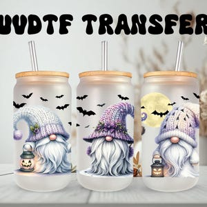 Könnte beinhalten: Drei Gläser mit Bambusdeckeln und Metallstrohhalmen. Jedes Glas zeigt ein Aquarell-Zwerg-Design mit langem weißem Bart, einer Laterne und einer Strickmütze. Schwarze Fledermäuse fliegen um die Zwerge. Der Text "UVDTF TRANSFER" steht oben.