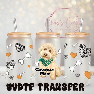 Puede incluir: Tres vasos de vidrio esmerilado con tapas de bambú y pajitas. Cada vaso presenta un diseño diferente: uno con un perro blanco con una bandana verde y el texto "Cavapoo Mom", otro con un patrón de corazones naranjas y huellas de patas negras, y otro con un patrón de corazones naranjas y huesos blancos.