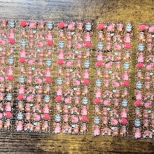 May include: Sheets of stickers featuring various sloth designs. The stickers showcase sloths in different poses, some wearing face masks, holding donuts, and with pink flamingos. The stickers are in shades of brown, pink, and blue.