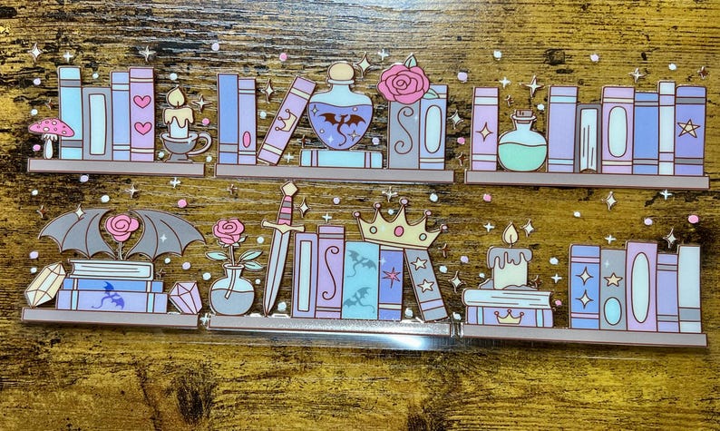 May include: A whimsical illustration of two shelves filled with fantasy-themed books, potions, and decorative elements. The design features pastel colors, including blue, purple, and pink, with accents like a dragon, a crown, and a sword. Stars and sparkles add to the magical aesthetic.