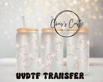 May include: Three frosted glass tumblers with a design of white stars and pink string lights. The tumblers have wooden lids and clear straws. The text "UV DTF TRANSFER" is at the bottom of the image.