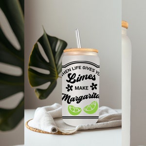 May include: A white frosted glass can with a bamboo lid and a straw. The can has a black graphic that says "When life gives you limes, make margaritas" with two green lime slices.