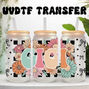 May include: Three frosted glass beverage cups with wooden lids and straws. Each cup features a floral design with the name "GIGI" in colourful letters. The cups are decorated with black and white chequered patterns and polka dots. The text "UVDTF TRANSFER" is at the top.