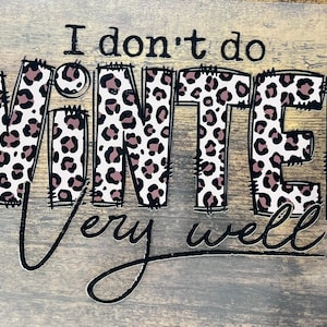 May include: A wooden sign with the phrase "I don't do WINTER very well." The word WINTER is in a leopard print pattern with a tan beanie on the letter "W". The text is in black and the background is a light gray wood.