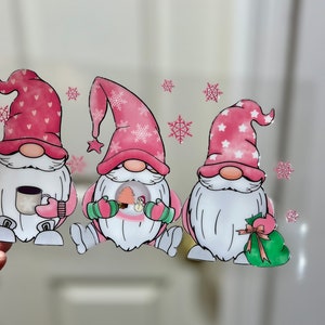 May include: Three pink gnomes with white beards and hats. The gnome on the left is holding a mug, the gnome in the middle is holding a snow globe, and the gnome on the right is holding a green gift bag.