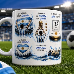 May include: A white ceramic mug featuring a graphic print of Lionel Messi holding a trophy, the Argentine flag, and text including "Soy hincha de la selecci&oacute;n," "Ganamos la tercera con Lionel," "32 a&ntilde;os despu&eacute;s," and "Queremos ser campeones otra vez."