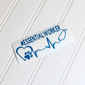 Könnte beinhalten: Ein blauer Vinyl-Aufkleber mit einem Pfotenabdruck in einem Herzen und einer Herzschlaglinie. Der Aufkleber lautet "#ESSENTIAL WORKER".