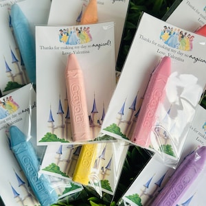 Puede incluir: Un conjunto de seis tizas de colores empaquetadas en bolsas de plástico transparentes con tarjetas de agradecimiento con temática de princesas. Las tarjetas presentan una ilustración de un castillo y el texto "¡Gracias por hacer que mi día sea tan mágico! Con cariño, Valentina".