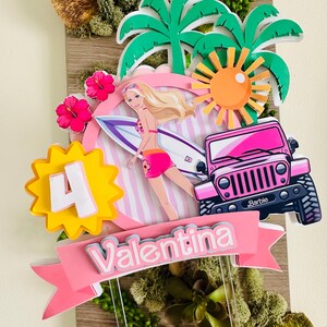 May include: A vibrant cake topper with a Barbie theme. It features a pink jeep, a surfboard, palm trees, a sun, and the number 4. The name "Valentina" is displayed on a pink banner. The topper is decorated with pink and green accents.
