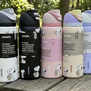 May include: A collection of Owala insulated water bottles in various colors, including white, black, pink, beige, and purple. Each bottle features a Snoopy design and the text "Hi there. I'm leak proof. I'm insulated. And I have a built-in straw." The bottles are 32 oz.