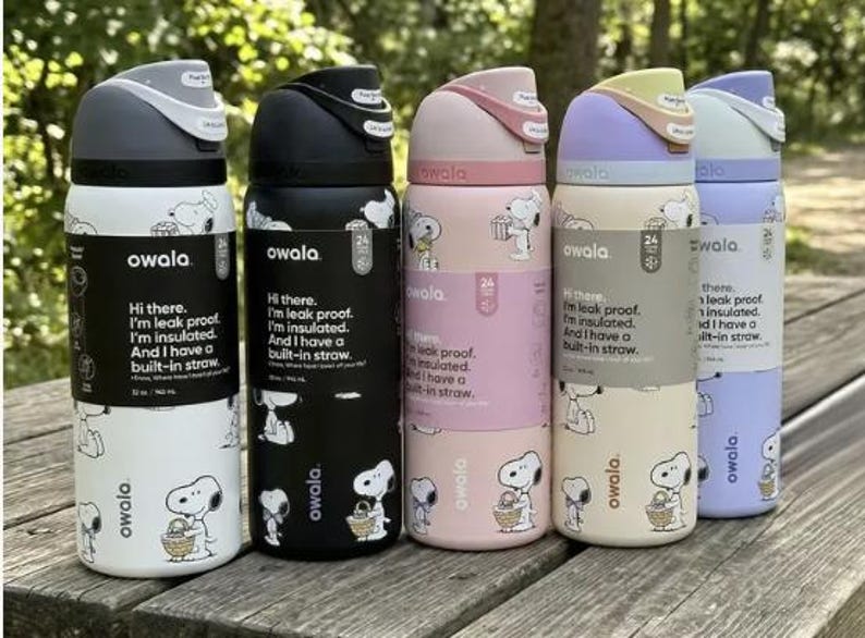 May include: A collection of Owala insulated water bottles in various colors, including white, black, pink, beige, and purple. Each bottle features a Snoopy design and the text "Hi there. I'm leak proof. I'm insulated. And I have a built-in straw." The bottles are 32 oz.