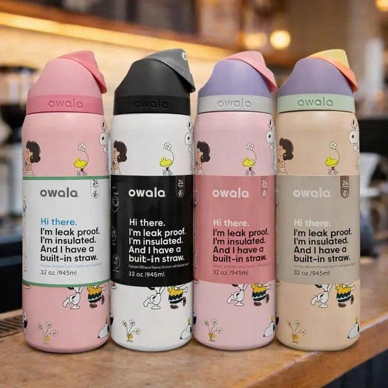 May include: Four Owala insulated water bottles, each with a different color lid and base. The bottles feature a cartoon design and text that reads "Hi there. I'm leak proof. I'm insulated. And I have a built-in straw. 32 oz./945ml."