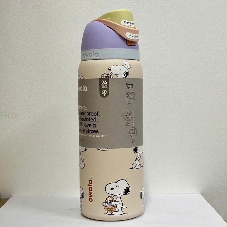 May include: A beige Owala water bottle with a Snoopy design. The bottle has a purple lid and a push-button mechanism. The bottle is insulated and leak-proof, with a built-in straw. The bottle is designed to keep drinks cold for 24 hours.