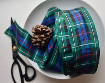 May include: Green, blue, red, and white plaid ribbon with a satin finish. The ribbon is rolled up on a white plate.