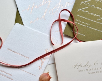 May include: A collection of wedding stationery featuring white and olive green cards with elegant calligraphy in a copper color. A red ribbon weaves through the cards. The text includes names, addresses, and RSVP details.