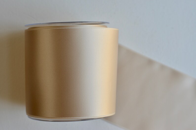 May include: A spool of beige satin ribbon wrapped in clear plastic.