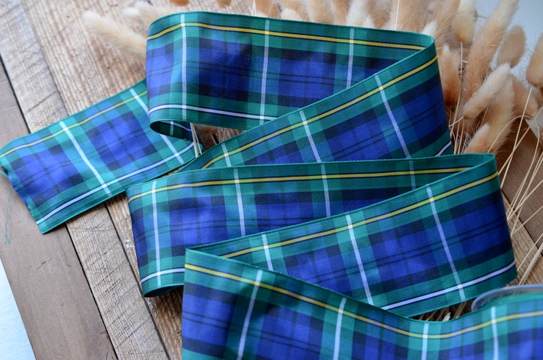 May include: Blue, green, and yellow plaid ribbon with a satin finish. The ribbon is folded in a decorative way.