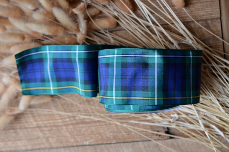May include: Green, blue, and yellow plaid ribbon with a white stripe. The ribbon is folded and tied in a knot.
