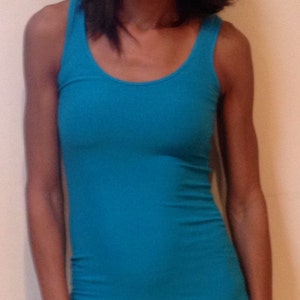 May include: A woman wearing a turquoise tank top and black pants.