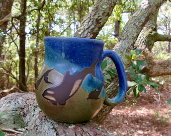 Dolphins and a pair of orcas  play across this obx coffee mug