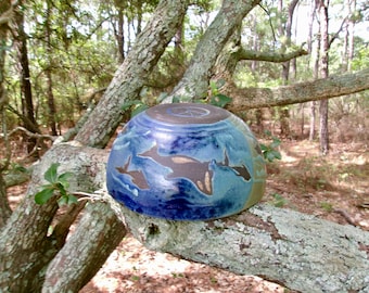 Dolphins and orcas swim together around the outside of this large unique serving bowl