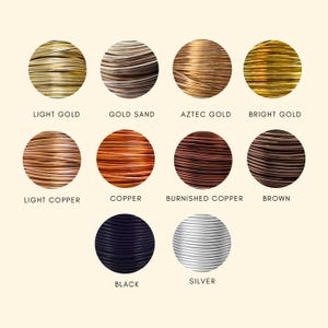 May include: A collection of eleven circular spools of craft wire in various metallic and solid colors, labeled Light Gold, Gold Sand, Aztec Gold, Bright Gold, Light Copper, Copper, Burnished Copper, Brown, Black, and Silver, arranged in rows.