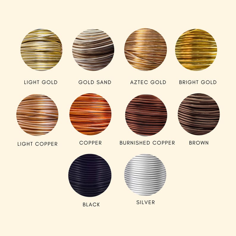 May include: A collection of eleven circular spools of craft wire in various metallic and solid colors, labeled Light Gold, Gold Sand, Aztec Gold, Bright Gold, Light Copper, Copper, Burnished Copper, Brown, Black, and Silver, arranged in rows.