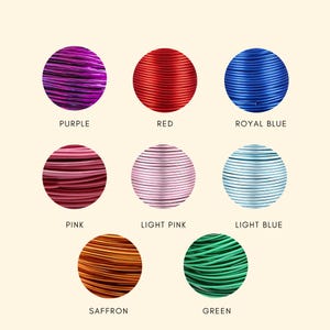 May include: Eight circular coils of colored craft wire arranged in a grid. The colors are labeled as purple, red, royal blue, pink, light pink, light blue, saffron, and green. Each coil shows a metallic finish and a consistent, thin, round wire texture.