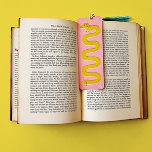 May include: A pink and yellow bookmark with a cartoon dachshund illustration. The bookmark features the text "When She Was Good: Bo" and a quote from the book.