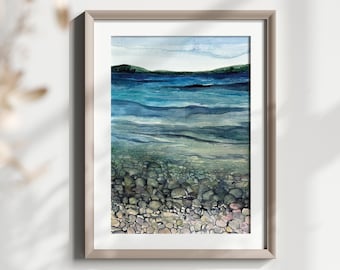 May include: Watercolor painting of a rocky beach with a blue ocean and a green island in the background.