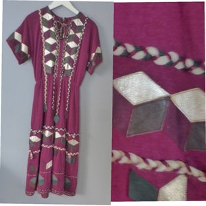 May include: A long, burgundy dress with a geometric pattern of brown, gold, and white leather. The dress has a short sleeve and a gathered waist.
