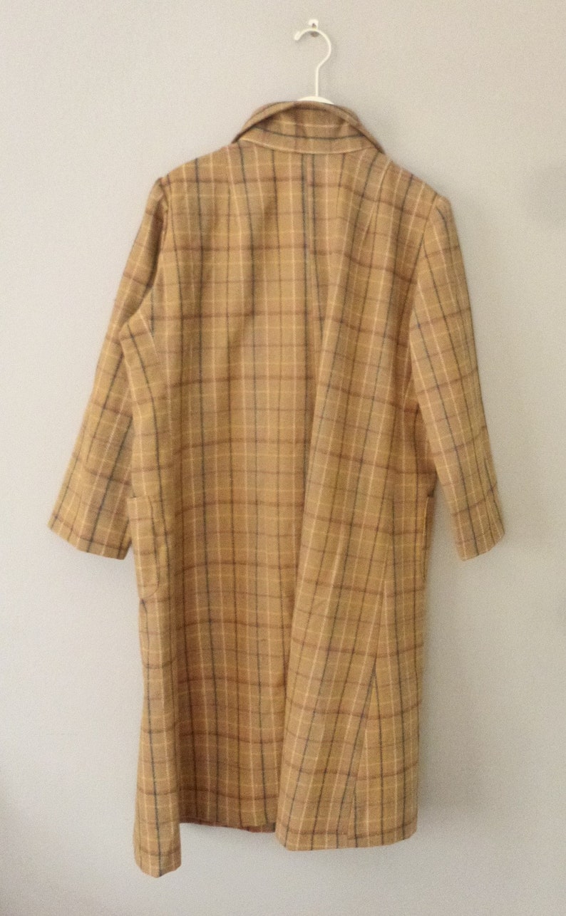May include: A long-sleeved, brown and tan plaid coat with a collared neckline. The coat is hanging on a white hanger.