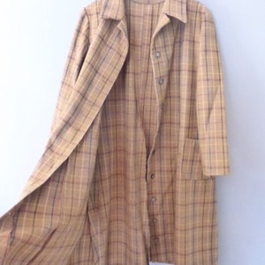 May include: A long, brown and tan plaid coat with a button-up front and a single pocket on the left side. The coat is open and the lining is visible.