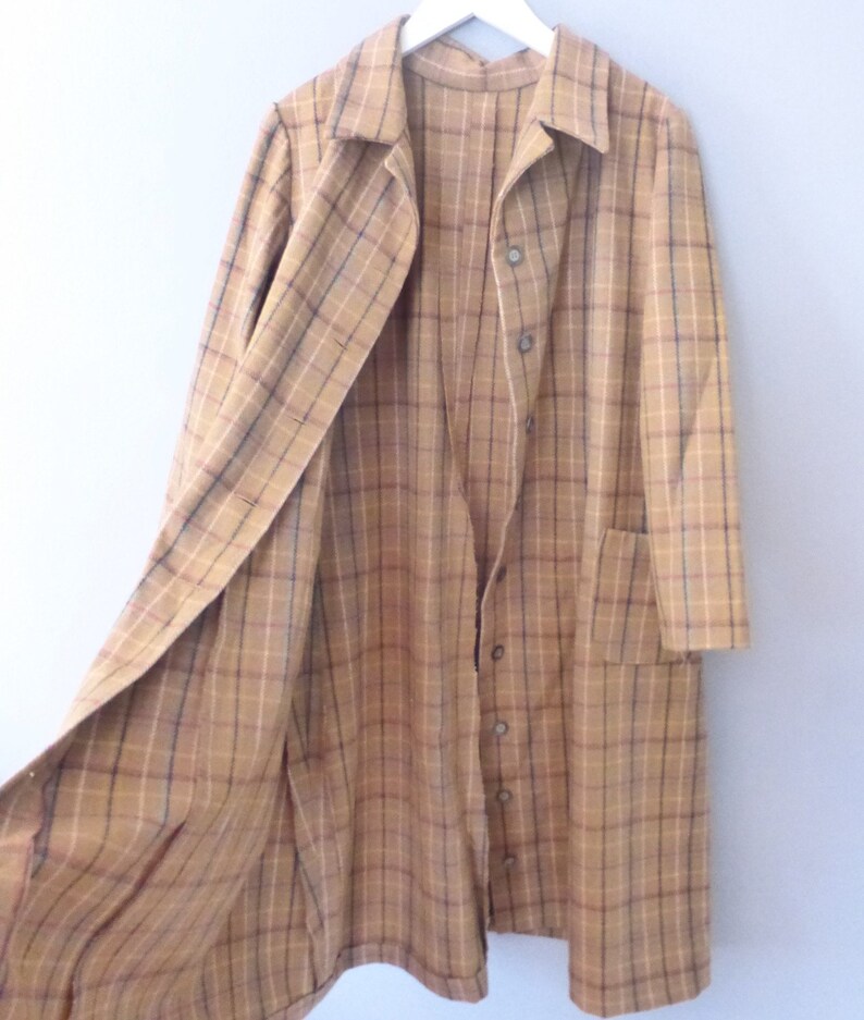 May include: A long, brown and tan plaid coat with a button-up front and a single pocket on the left side. The coat is open and the lining is visible.